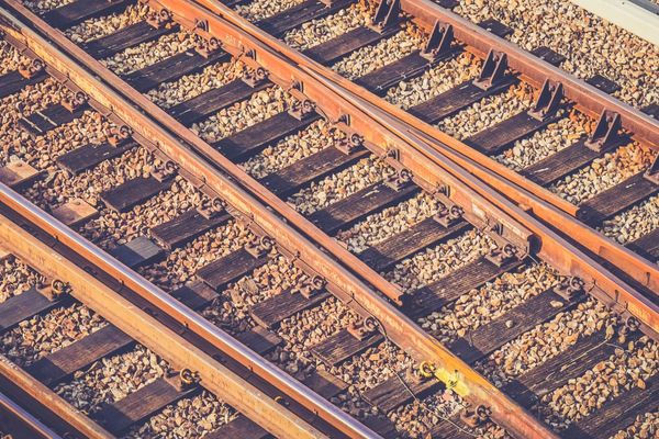 Rusty-hued closeup photograph of tracks running through a train yard